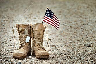 Old military combat boots with dog tags and a small American flag