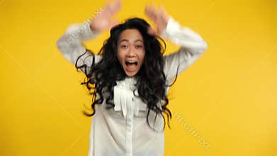 Ecstatic asian woman jumping with joy and arms up celebrating success