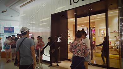 Unidentified people stand on the queue at Louis Vuitton Luxury boutique shop