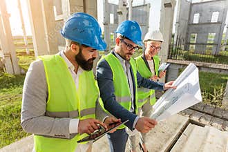 Mixed group of young architects and civil engineers or business partners meeting on a large construction site