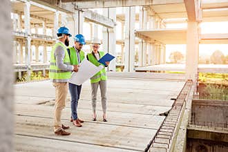 Mixed team of young engineers inspecting work progress on a large construction site