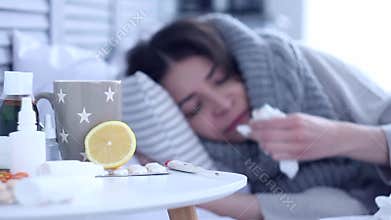 Sick woman lying on bed with flu at grey bedroom
