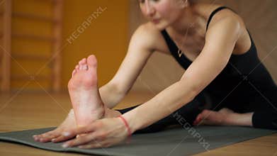 Stretching close up. Girl doing split twine. Hanumanasana, monkey pose. Young oriental appearance woman practicing yoga