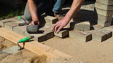 The builder is laying paving stones.