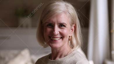 Happy mature woman looking at camera posing for video portrait