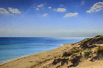 Summer seascape,Apulia coast: Marina di Lizzano beach Taranto. In the foreground dunes with lush mediterranean scrub.