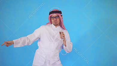Arab man in headphones stands on a blue background and vigorously dancing to the music