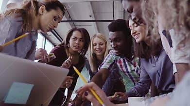 Close-up view of young business team with female team leader working together near the table, actively brainstorming.