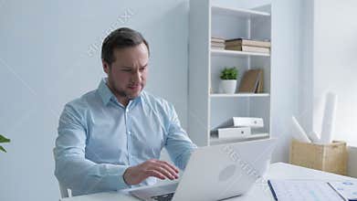 Tired man massaging neck while working on laptop