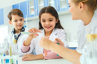 Little kids with teacher in school laboratory making experiment
