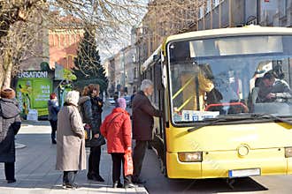 Group of people waiting in queue to enter local city bus on bus stop station