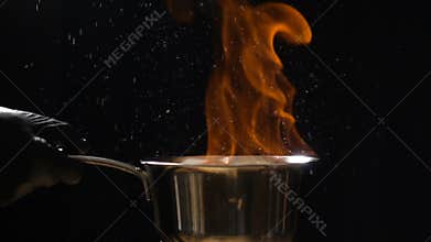 Stirring pan with burning sauce and hot droplets