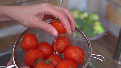 Woman`s hands is washing ripe tomatoes at her kitchen