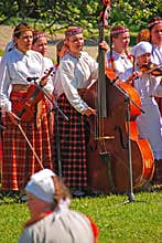 Young girls enjoy playing musical instrument during Latvian outdoor Folk Festival at Turaida field, Latvia