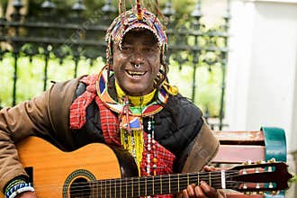 Street artist colourful clothes singing with guitar