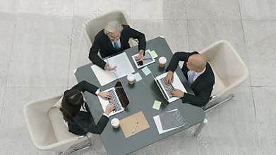 High angle view of three corporate business people meeting in office