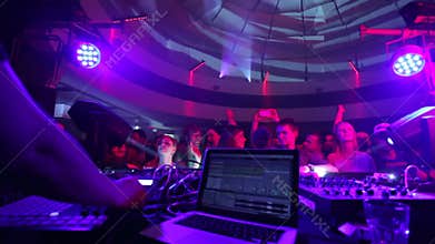Clubbing people on dance floor as DJ performs music set