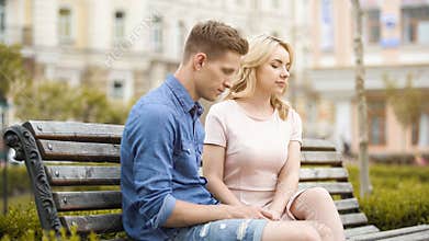 Couple feeling awkward, sitting on bench in silence, crisis in relationship