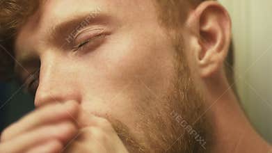 Close-up side face of the tired, ill and almost asleep blond curlyhead man, coughing.