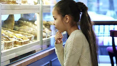 Cute little girl looking at the display at the local bakery