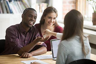 Happy multiracial couple getting keys to new home from realtor