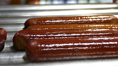 Sausages are heated for hot dogs. Preparing the French hot dog. Spinning sausages on the grill. Fast food