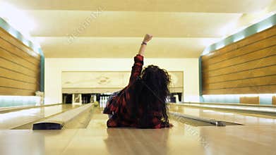 Young woman falls down while throws a bowling ball
