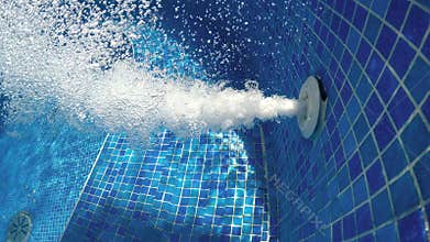 Air bubbles from jacuzzi jet in bubbly blue water in a thermal spa pool