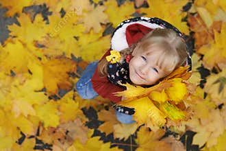 Autumn street portrait of the little girl holding a bunch of maple leaves