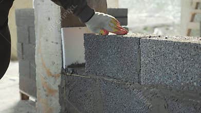 Construction worker builds brick wall, closeup view at construction site
