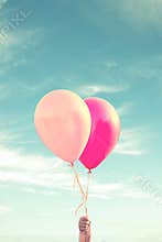 Hand of a child holding balloons, sky background