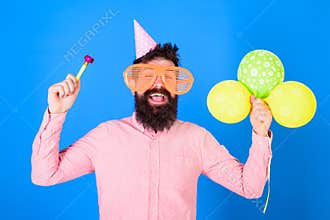 Man with beard and mustache on happy face holds air balloons, blue background. Party concept. Hipster in giant