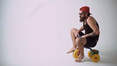 A funny bearded man is riding a children`s bicycle