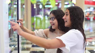 Two girls use the interactive panel in the mall. girls choose the goods with the help of an interactive panel.