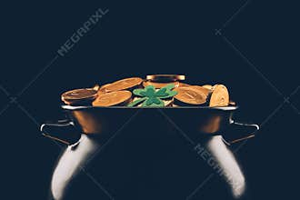 black pot with golden coins isolated on black, st patricks day concept