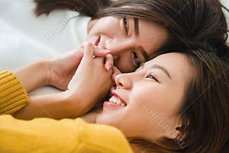 Beautiful young asian women LGBT lesbian happy couple hugging and smiling while lying together in bed under blanket at home.