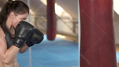 Beautiful boxing woman training with punching bag in fitness studio. Fierce strength. Female fit body. Slow motion.