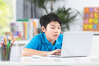 Asian cute boy using laptop computer.