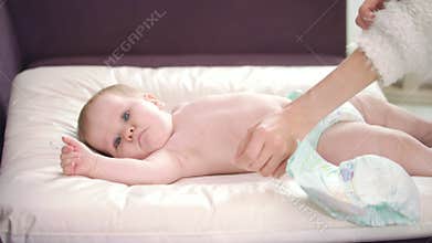 Mom putting child to change diapers. Mothercare baby