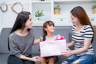 Happy of mother and daughter woman asian and aunt with gift with pink ribbon and daughter kissing mother