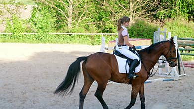 Summer, outdoors, girl rider, jockey riding on a thoroughbred beautiful brown stallion, horse, on the training ground