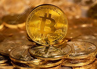 Single Bitcoin coin standing on top of other gold coins