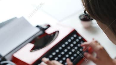 Woman hand typing on red vintage typewriter