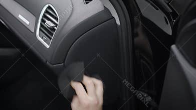 Man is cleaning control panel inside a car, rubbing it by soft cloth, removing dust and dirt, close-up