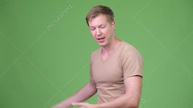 Young handsome Scandinavian man presenting something against green background
