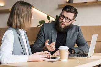 business partners having conversation in modern cafe with devices and coffee