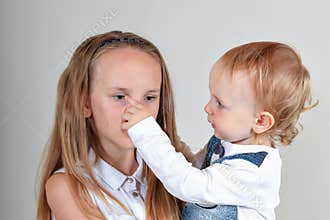 Closeup portrait of a brother and sister. A girl is frowning, and a child is trying to cheer her up. true emotions.