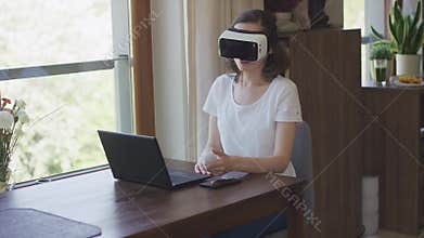 Young woman sitting at laptop in VR headset