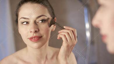 Young woman applying makeup by rouge