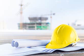 The yellow safety helmet and the blueprint at construction site